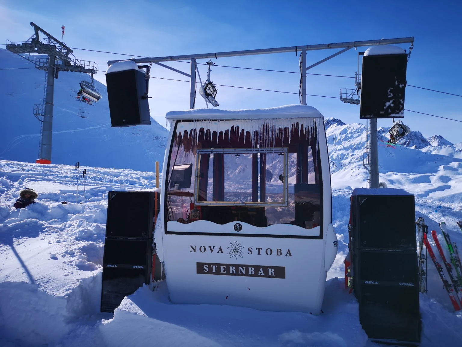 Die Sternbar in einer Gondelkabine mit Lautsprechern vor verschneiter Bergkulisse